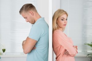 Side view of unhappy young couple standing back to back at home